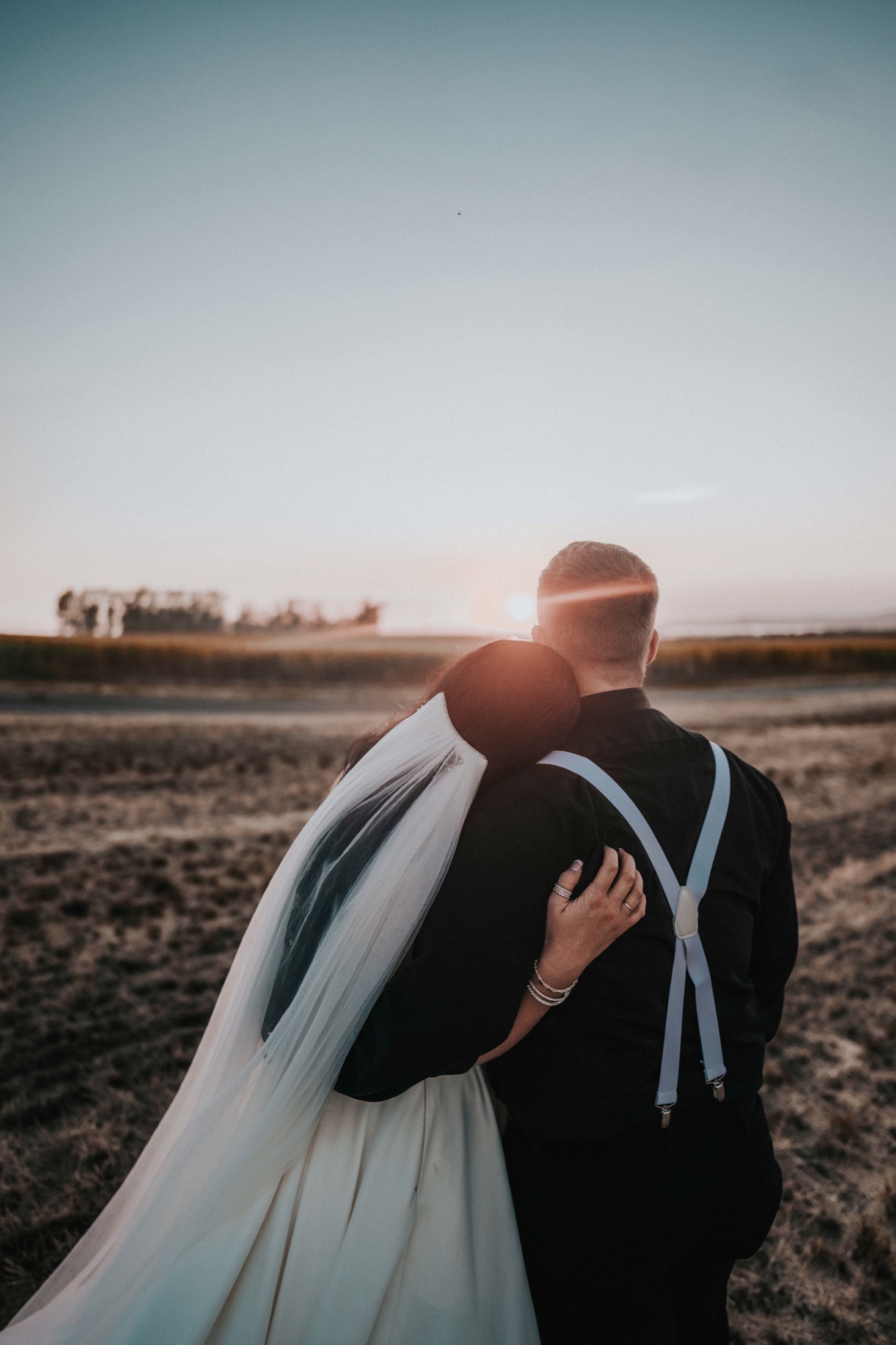 A couple holds each other in golden sunset light at their Southern California wedding